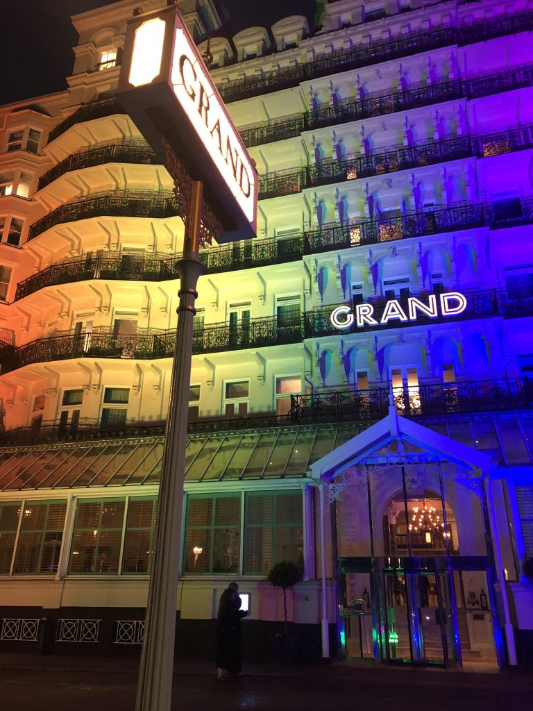 Grand Brighton Hotel lit up in rainbow colours of orange, yellow, green and blue.