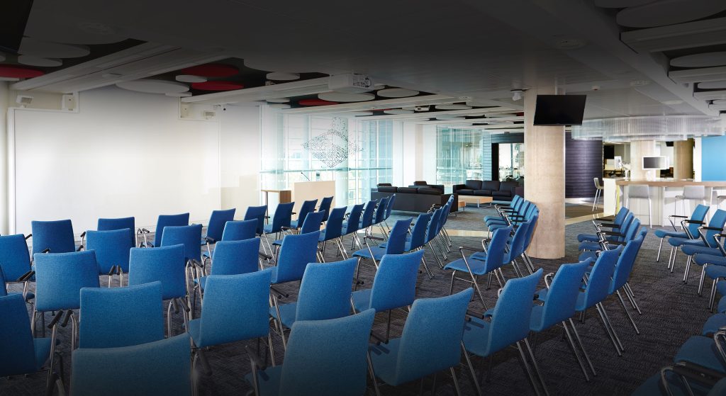 A room set up for a presentation with 6 rows of blue chairs