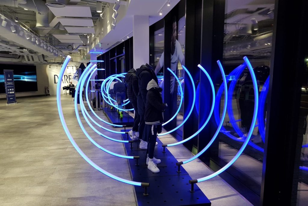 An interior image of a retail store, with mannequins in the window and blue lights arching up behind the mannequins