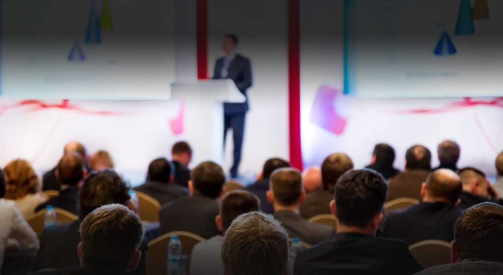Man delivering a talk at a podium in front of a room of people