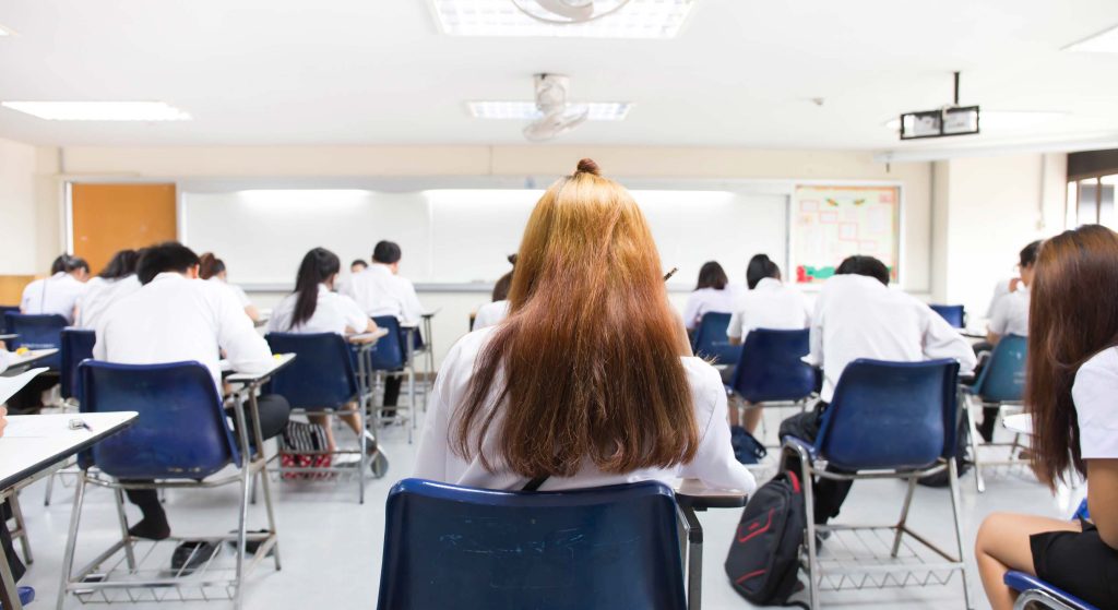 A classroom of children all sitting down and facing away from the camera. Exam-style scenario