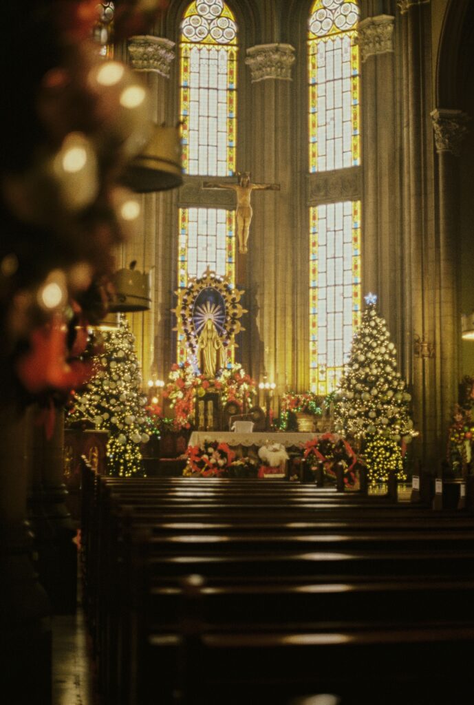 A festive scene in a church featuring Christmas trees and lights